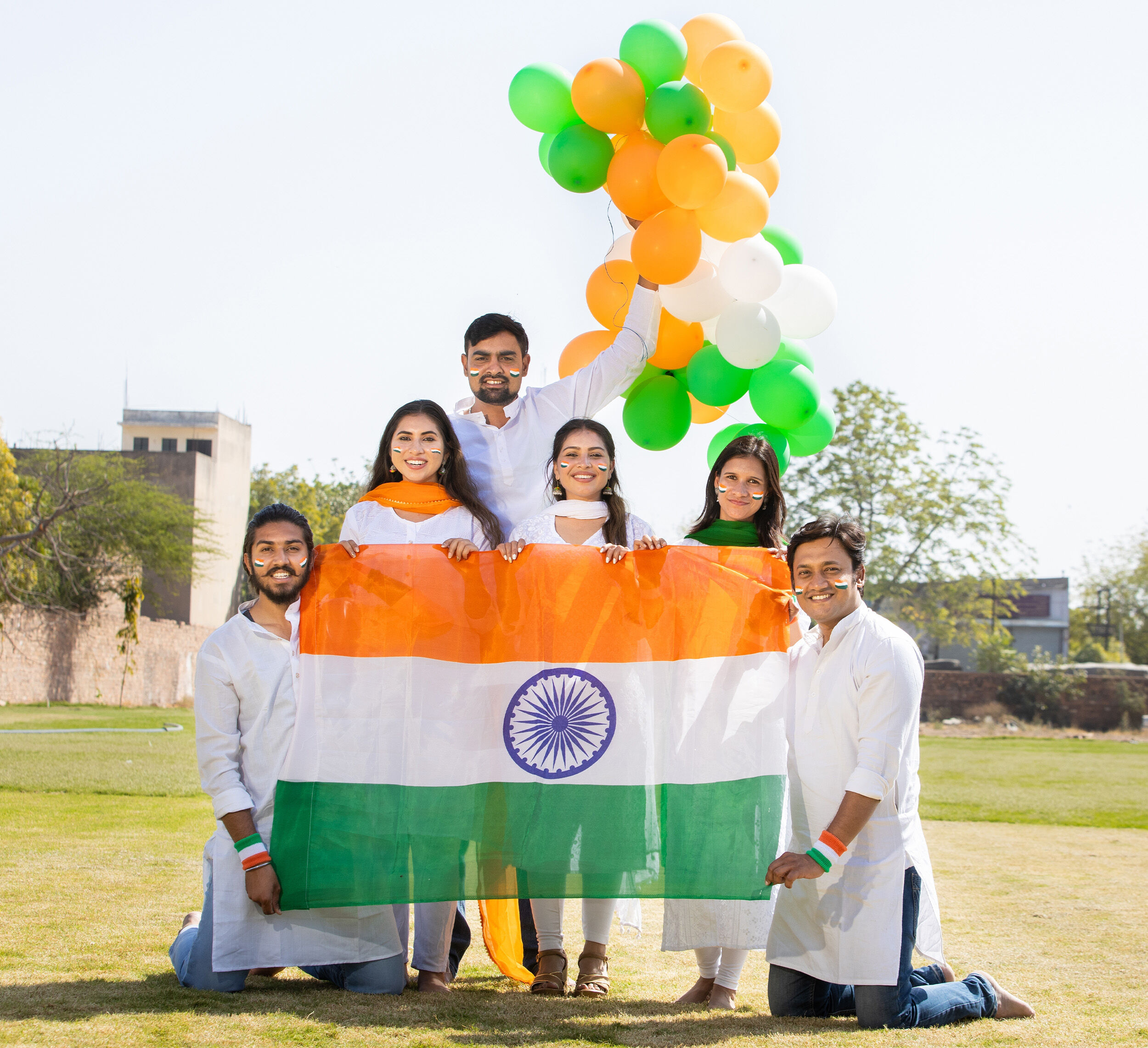 Family celebrating Independence Day with the Indian flag and tricolour balloons during a community gathering.